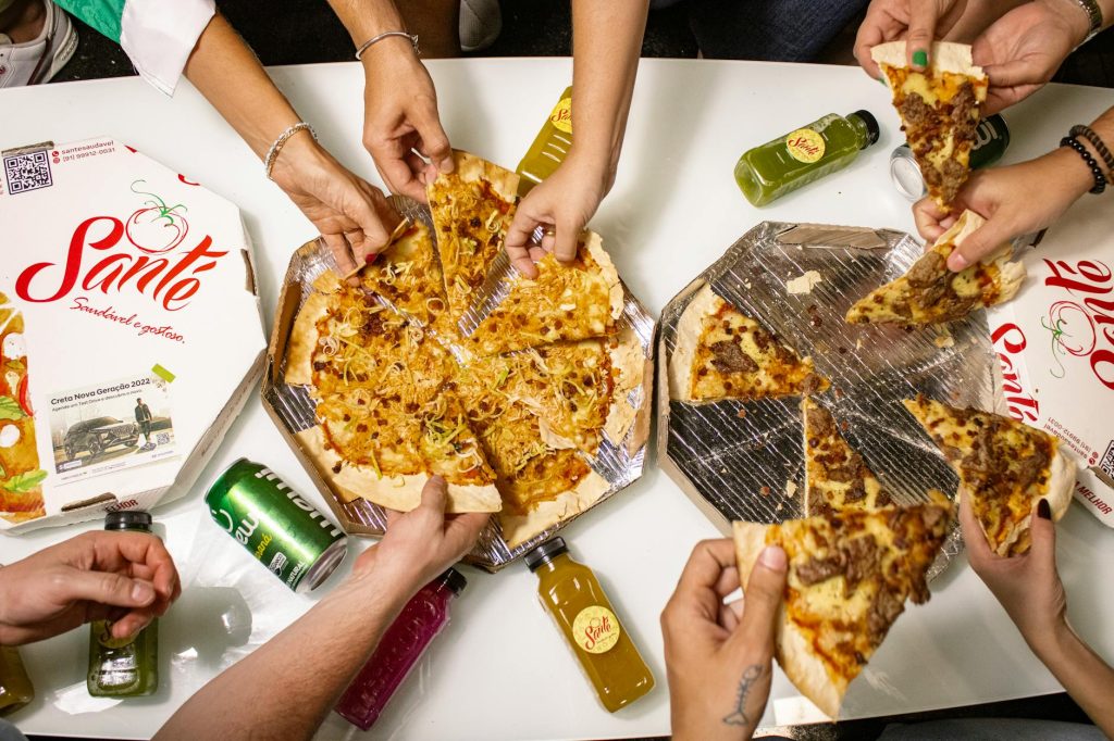 Top view of friends sharing pizza slices with drinks, perfect for a casual dining theme.