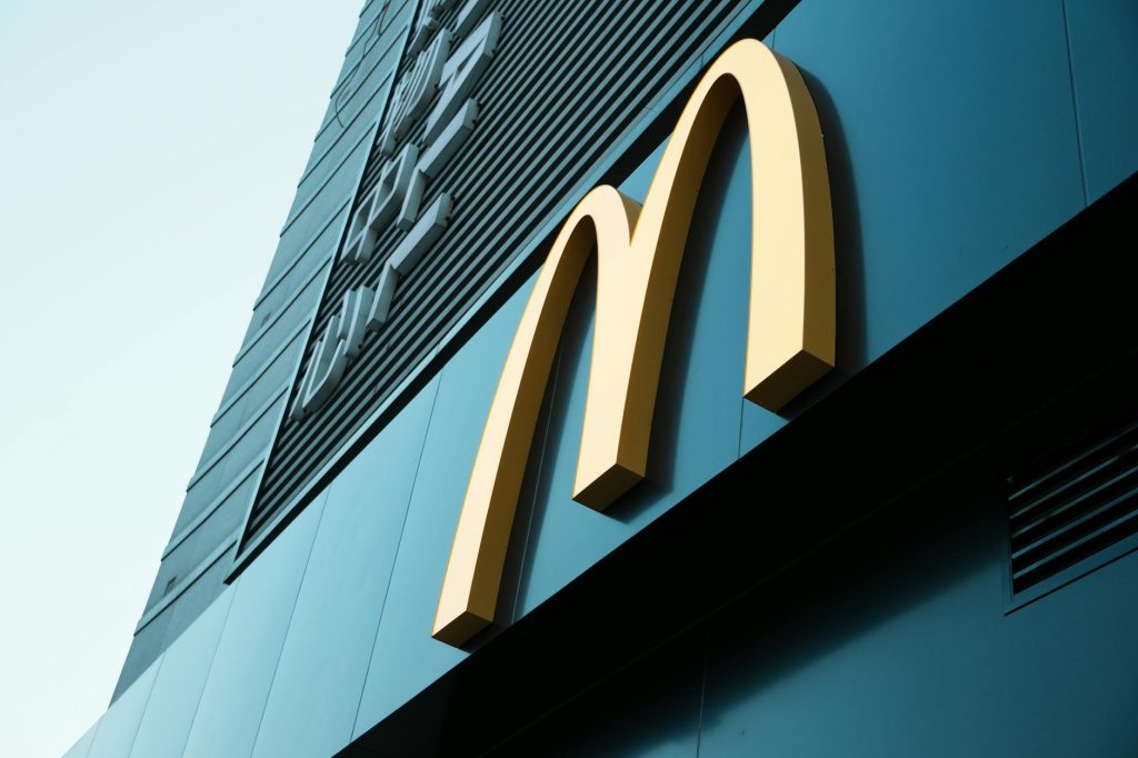 Large fast food restaurant golden arch sign on a modern building facade.